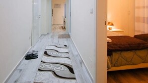 Un pasillo con alfombra estampada que conduce a un dormitorio con cama y mesita de noche.