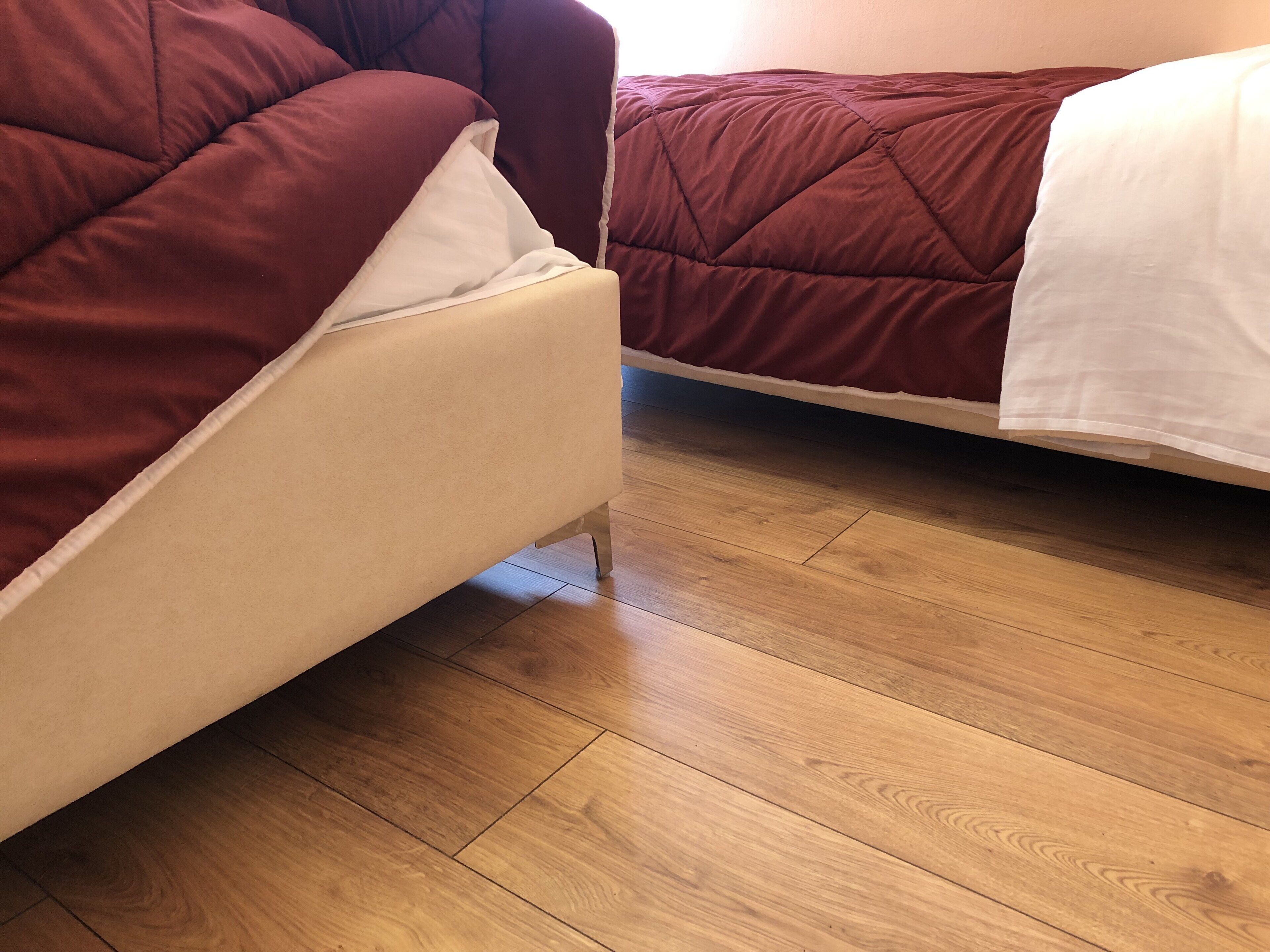 Ein Zimmer mit zwei Betten, jeweils mit einer roten und weißen Bettdecke, und Holzböden.
