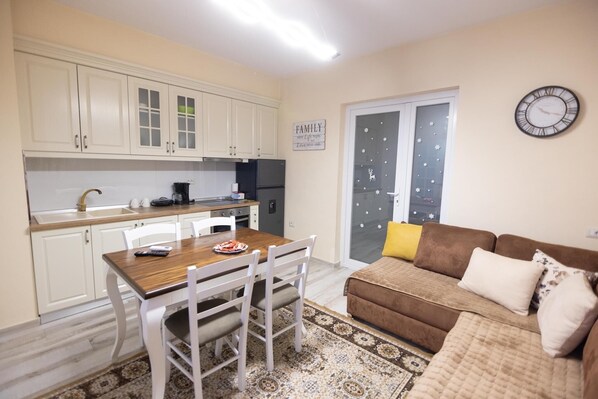 Un espacio habitable compacto con kitchenette, comedor y sofá.