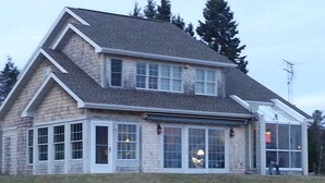 A two-story house with a large front porch, multiple windows, and a garage. - Stunning House on the Bay in the Beautiful Upper Penninsula of Michigan (Cedar River)