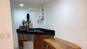 Eine kompakte Küche mit Mikrowelle, Kaffeemaschine und kleinem Kühlschrank.