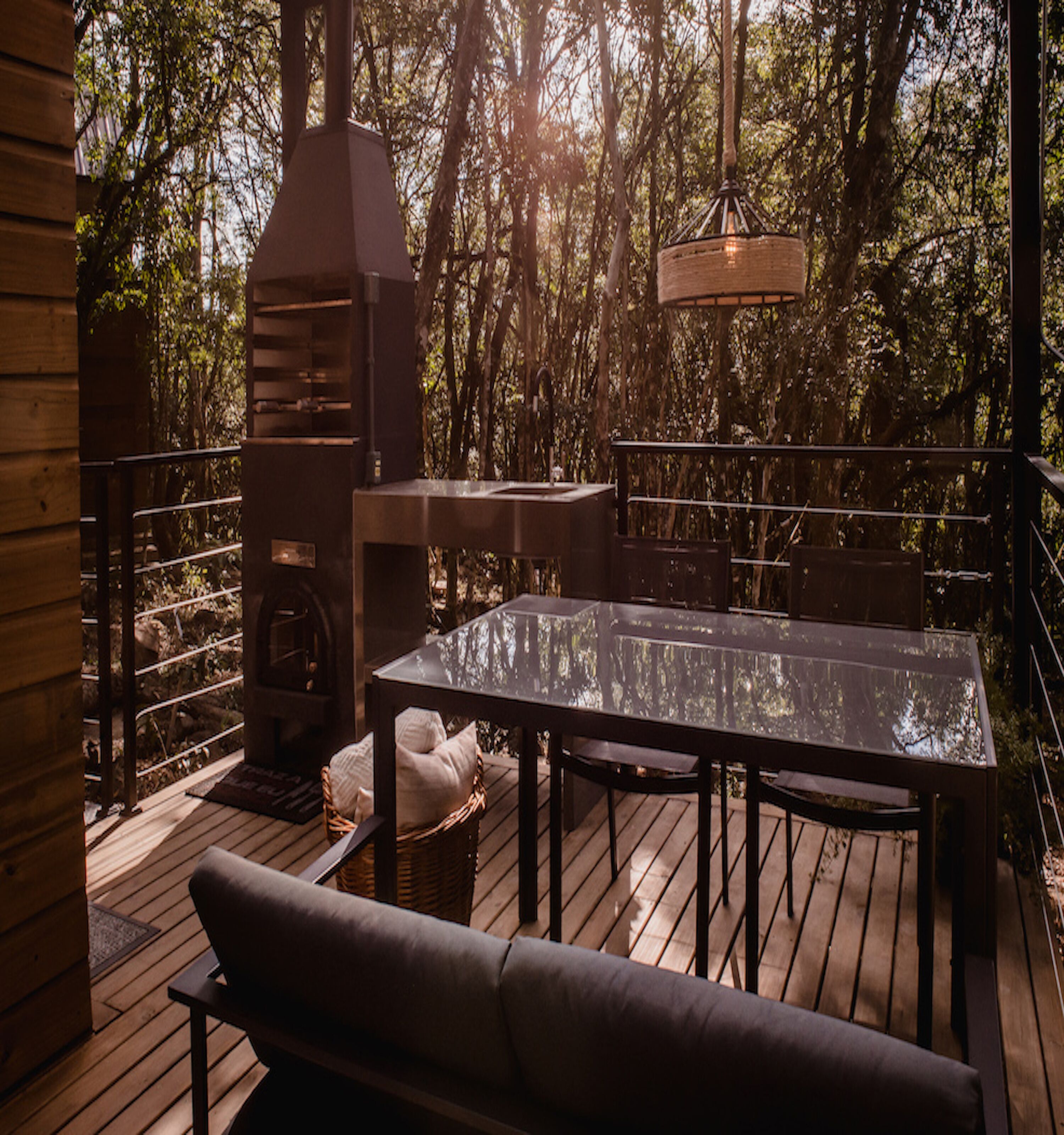 Une terrasse extérieure avec une table et des chaises, un barbecue et un luminaire suspendu.