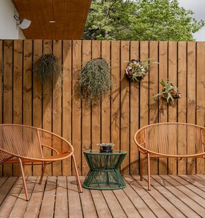 A wooden deck with two wicker chairs and a small green table. - Vila Nambu (Gramado)