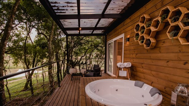 A wooden deck with a hot tub, outdoor seating, and hexagonal planters on the wall. - Vila Nambu (Gramado)