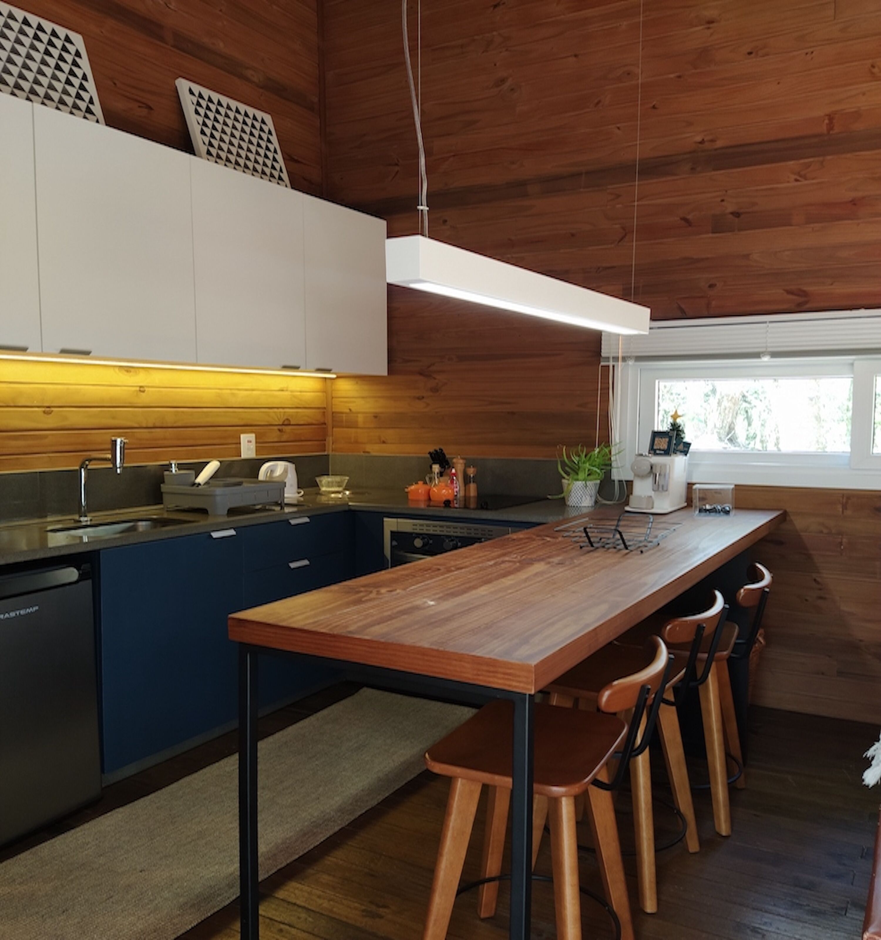 Una cocina moderna con una isla de madera, taburetes de bar y una ventana que proporciona luz natural.