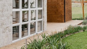 A modern house with large windows, a wooden deck, and a garden. - Vila Nambu (Gramado)