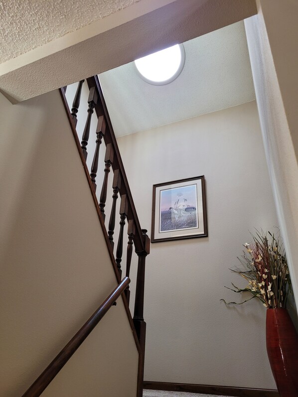 A staircase with wooden balusters, a framed picture on the wall, and a vase with flowers. - Lake front, pool and golf access, Sand Valley, Lake Arrowhead- 3 king beds! (Nekoosa)