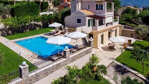 A two-story villa with a swimming pool, outdoor seating, and a view of the surrounding landscape. - Jasmine Luxury Villa With Private Pool (Corfu)