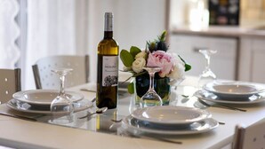 A dining table set with plates, cutlery, a wine bottle, and a vase with flowers. - Jasmine Luxury Villa With Private Pool (Corfu)