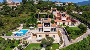 A hillside property with a swimming pool, stone walls, and lush greenery. - Jasmine Luxury Villa With Private Pool (Corfu)