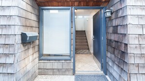 A wooden exterior with a mailbox, a sliding glass door, and a staircase leading inside. - Retro Split-Level Beach House | Steps to Sand | Darling Details Throughout! | Walk to Everything (Newport Beach)