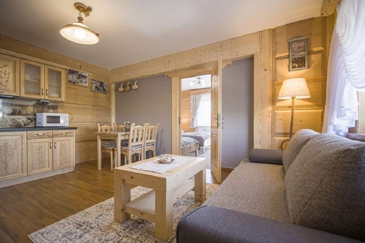 Un salon confortable avec un canapé, une table en bois et un coin cuisine équipé de placards et d’un four à micro-ondes.