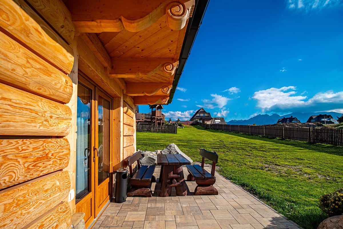 Une cabane en bois dotée d’un patio comprenant une table et des bancs en bois.