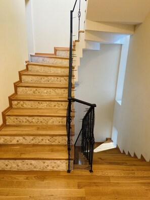 A wooden staircase with a black metal railing and a patterned floor.