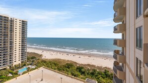 A high-rise hotel overlooking a beach with a pool and a clear sky. - $150 activities - E-gift card when you book - Balcony Access from Every Bedroom | Oceanview | MG1108 (Myrtle Beach)