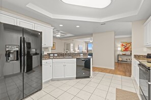 A modern kitchen with white cabinets, a black refrigerator, and a dishwasher.