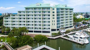 A multi-story hotel with balconies, located near a marina with boats docked.