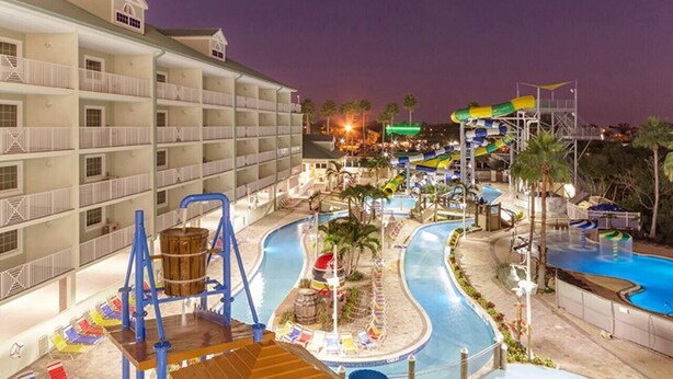 A hotel with multiple balconies, a pool area with slides, and a water park.