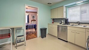 Una cocina con lavavajillas, pileta y armarios. Se puede ver un comedor con mesa y sillas a través de un acceso abierto.