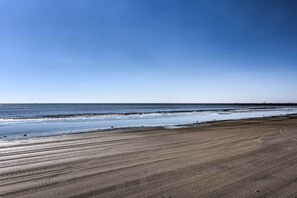 Ein Strand mit weitem Sandufer und ruhigem Wasser.
