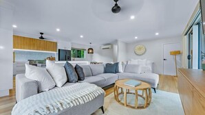 Una sala de estar moderna con un sofá seccional gris, una mesa de centro redonda de madera y una alfombra blanca.