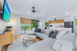 A modern living room with a grey sofa, a wooden coffee table, and a TV mounted on the wall.