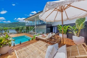 A modern outdoor lounge area with a pool, lounge chairs, and a large umbrella. - Airlie Abode (Jubilee Pocket)