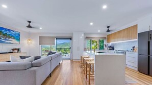 Cocina moderna con una isla central, suelo de madera y vista a zonas verdes.