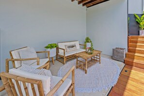 A wooden outdoor seating area with a round table and chairs, a small potted plant, and a concrete planter. - Airlie Abode (Jubilee Pocket)