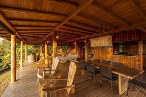 A covered outdoor area with wooden furniture, a bar, and a hanging light fixture. - 3BR Ocean View Villa w/ Pool + Included Breakfast (Cobano)