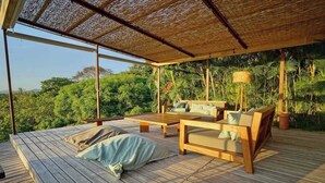Eine Holzterrasse mit einem Reetdach, einer Couch und einem Tisch.