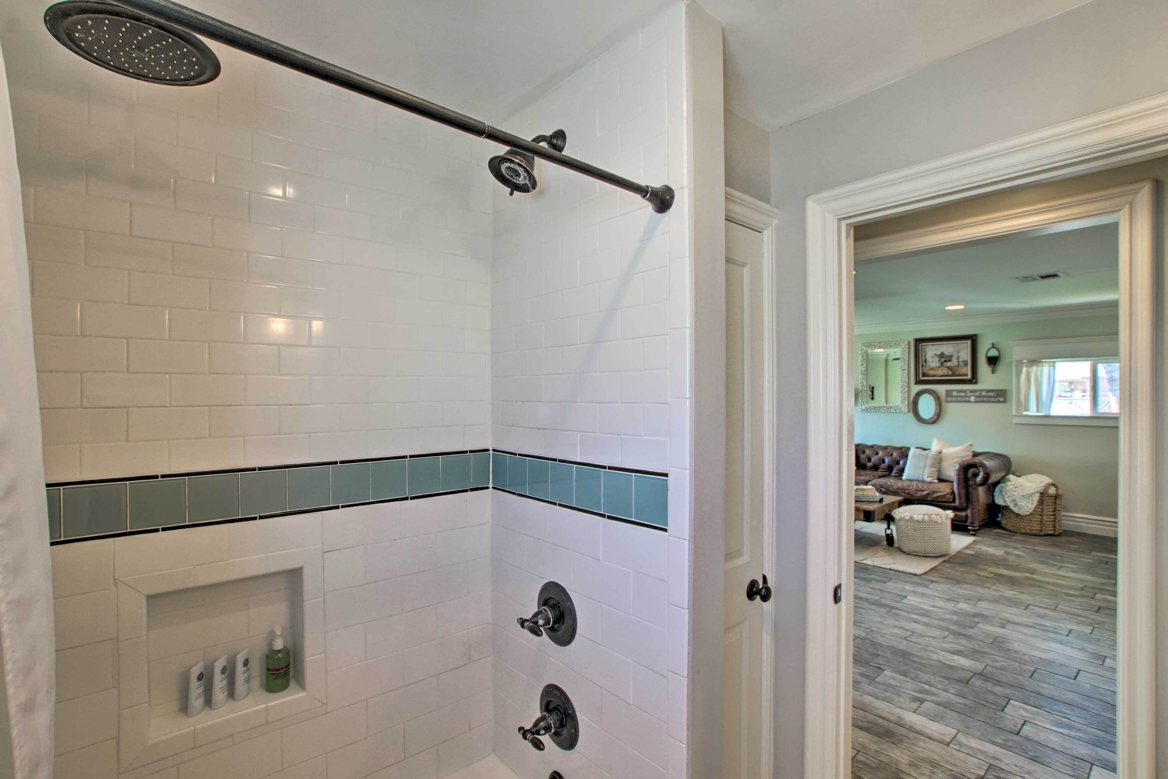 A bathroom with white subway tiles, a showerhead, and a towel rack.