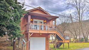 Una casa a due piani in legno con un balcone, un garage e una scala che conduce al piano superiore.