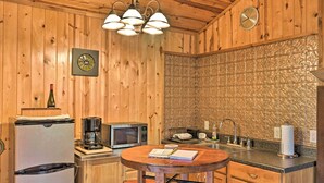 Una cucina in legno con frigorifero, microonde, macchina del caffè e un tavolo rotondo in legno con un quaderno.
