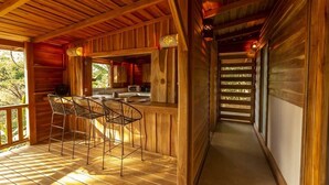 L’intérieur d’une cabane en bois comprend un coin cuisine, un bar avec des tabourets et un escalier.