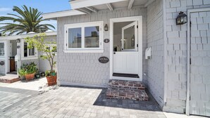 A building with a white exterior, a door with a window, and a small brick step leading to the entrance. - LOVELY DESIGNER COTTAGE!   3 MIN WALK TO THE BEACH AND HEISLER PARK! (Laguna Beach)