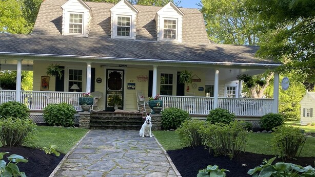 A two-story house with a front porch, a stone pathway leading to the entrance, and a well-maintained garden. - Charming Lakeside cottage , will sleep 10 (Bemus Point)