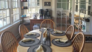 A dining area with a round wooden table set for six, surrounded by wooden chairs. - Charming Lakeside cottage , will sleep 10 (Bemus Point)