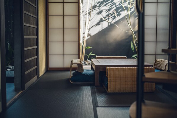 Una habitación japonesa tradicional con suelo de tatami, una mesita baja y mobiliario de fibras naturales.