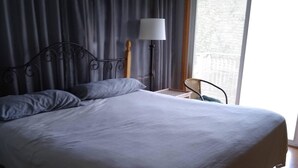 A bedroom with a large bed, a bedside table, a lamp, and a chair. - Peaceful retreat for all seasons' (Beaver Dam)