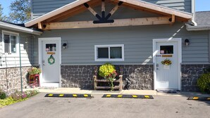 A two-story building with a stone facade, a wooden porch, and a flower arrangement at the entrance. - Peaceful retreat for all seasons' (Beaver Dam)