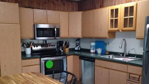 A kitchen with wooden cabinets, a stainless steel microwave, a stove, a sink, and a refrigerator. - Peaceful retreat for all seasons' (Beaver Dam)