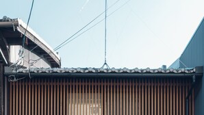 Un edificio japonés tradicional con fachada negra, puerta corredera de madera y una pequeña estructura negra a la derecha.