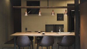 Una cocina moderna con una isla central, taburetes de bar, iluminación colgante y un lavamanos de acero inoxidable.