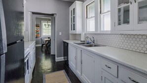 A kitchen with white cabinets, a dishwasher, and a tiled backsplash.
