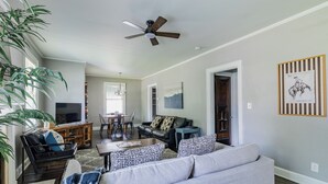 A living room with a sofa, coffee table, TV, and a ceiling fan.