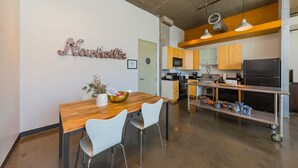 Una cocina moderna con una mesa de comedor de madera, sillas blancas y una isla de cocina con electrodomésticos.