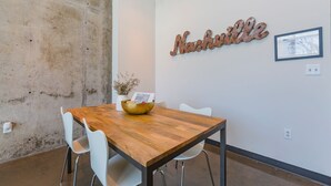 Una sala de conferencias con una mesa de madera, sillas blancas, un cuenco decorativo, una planta en maceta y un cartel en la pared que dice 'Nashville'.