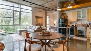 A spacious living area with a large round table, a sofa, and a kitchen area with cabinets and appliances. - Stylish Gulch Loft Close to Downtown Broadway (Nashville)