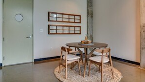 A dining area with a round table, four wooden chairs, and two wooden-framed mirrors on the wall. - Stylish Gulch Loft Close to Downtown Broadway (Nashville)